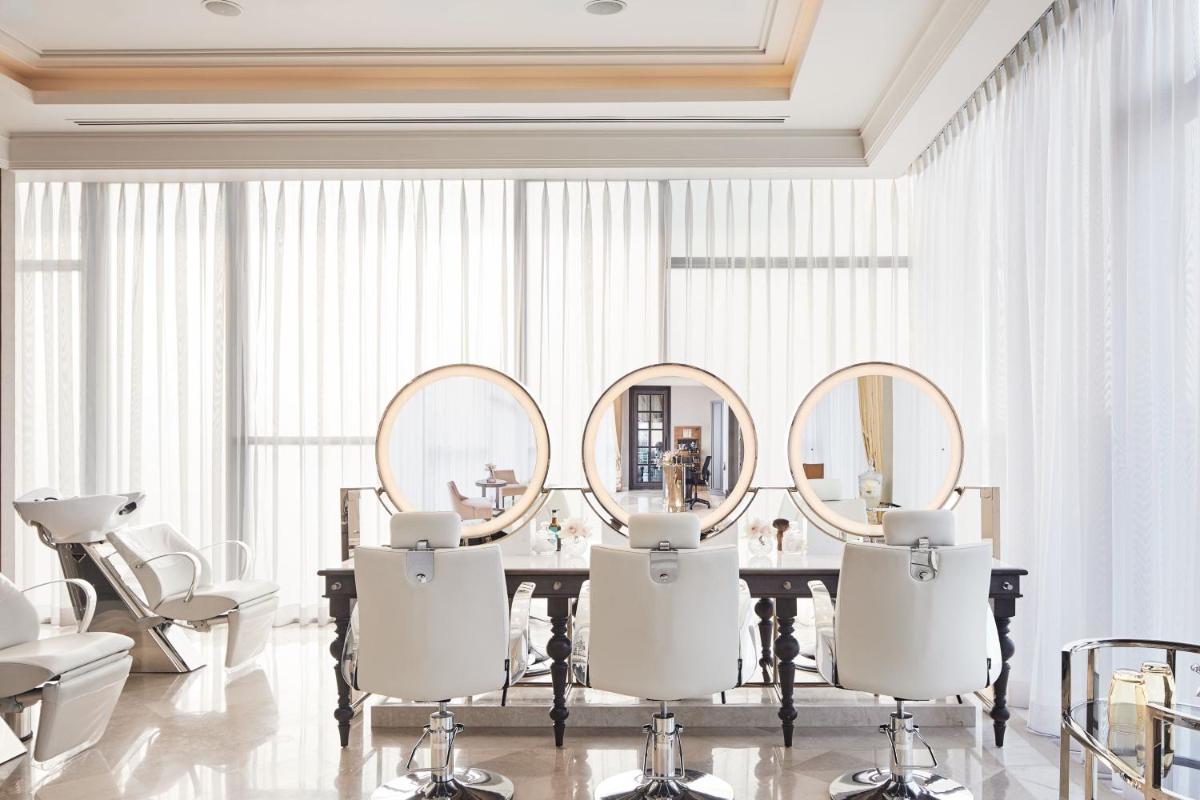a bathroom with mirrors and a table with white chairs at The Ritz-Carlton, Pune in Pune
