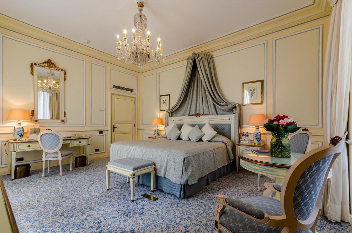 um quarto com uma cama, uma mesa e cadeiras em Olissippo Lapa Palace – The Leading Hotels of the World em Lisboa