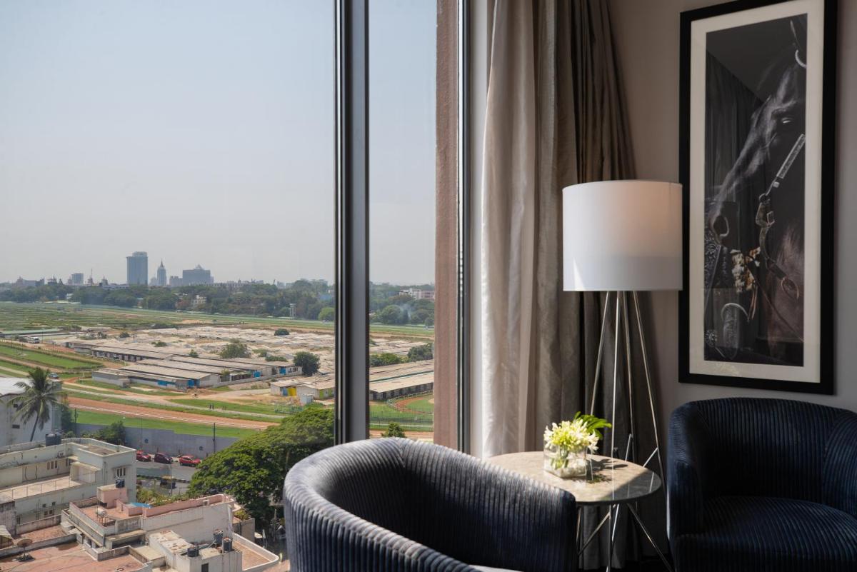 a room with two chairs and a table and a large window at Renaissance Bengaluru Race Course Hotel in Bengaluru