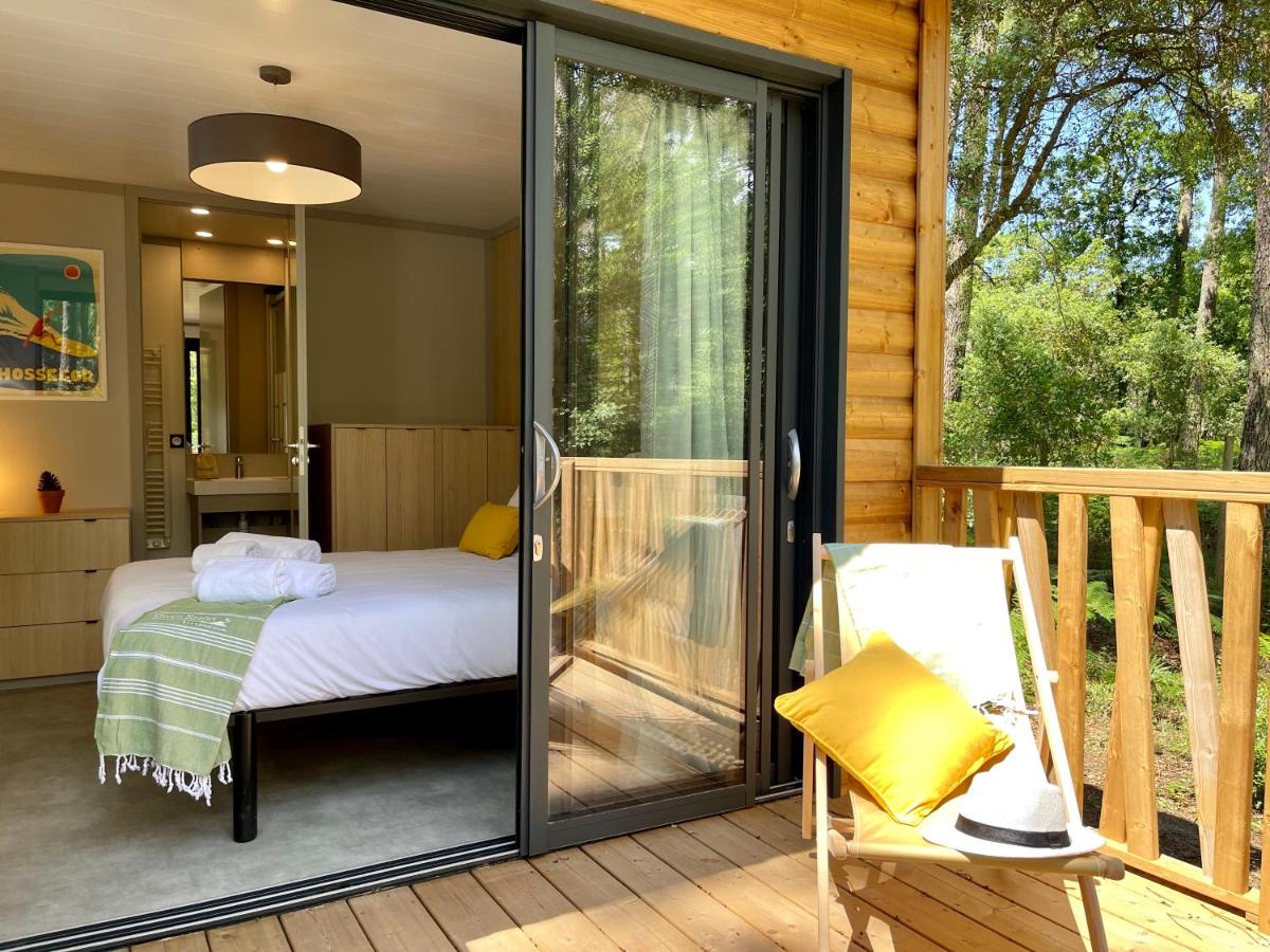 une chambre avec un lit et une porte coulissante en verre dans l'établissement Green Resort, à Ondres