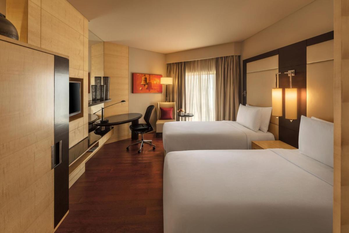 a hotel room with two beds and a desk at JW Marriott Mumbai Juhu in Mumbai