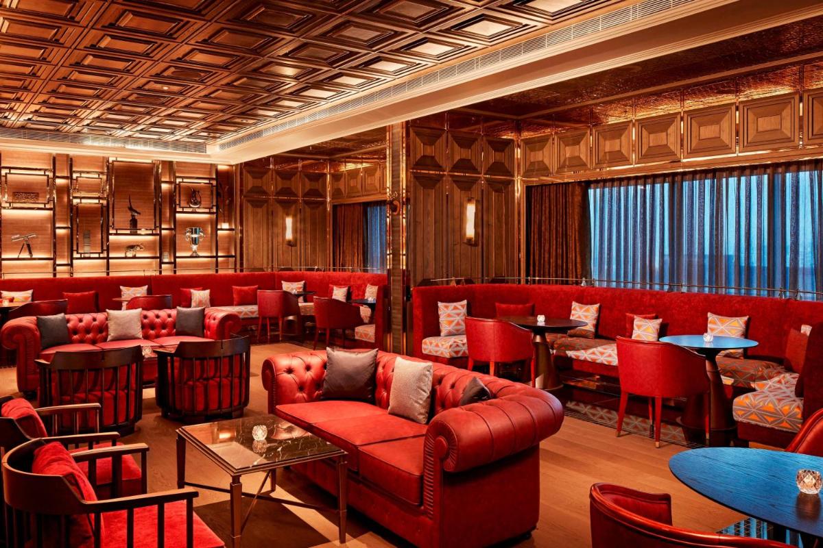 a restaurant with red furniture and tables and chairs at The Ritz-Carlton, Pune in Pune