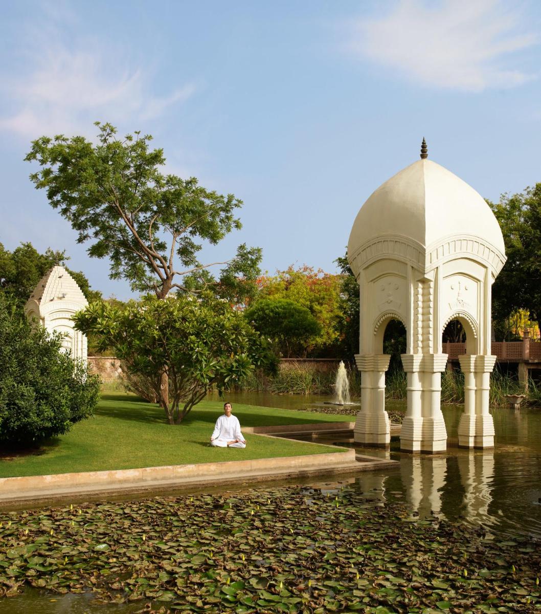 a woman in a white dress sitting in front of a fountain at The Oberoi Rajvilas Jaipur in Jaipur