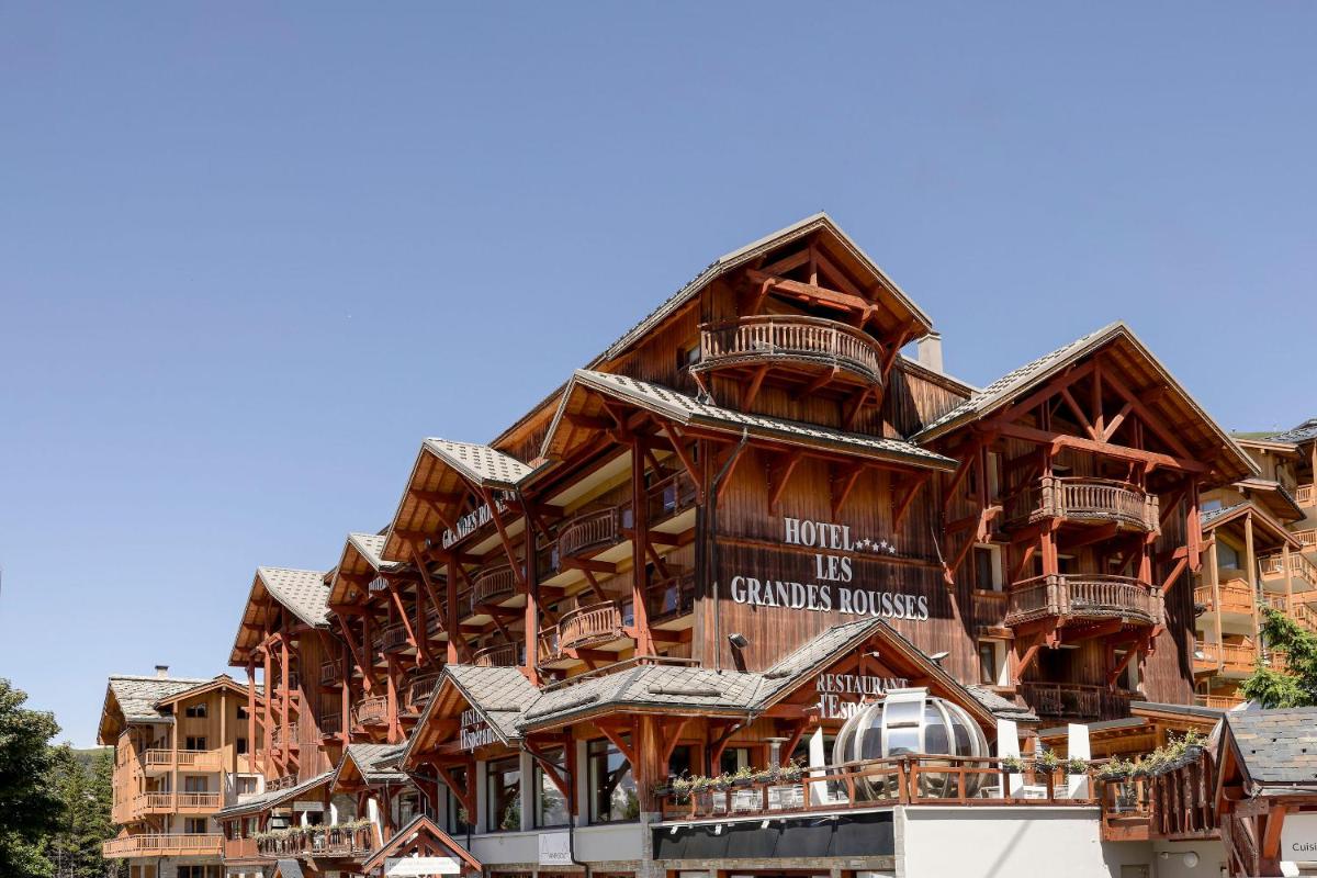 un grand bâtiment en rondins avec une enseigne dessus dans l'établissement Grandes Rousses Hotel & Spa, à L'Alpe-d'Huez