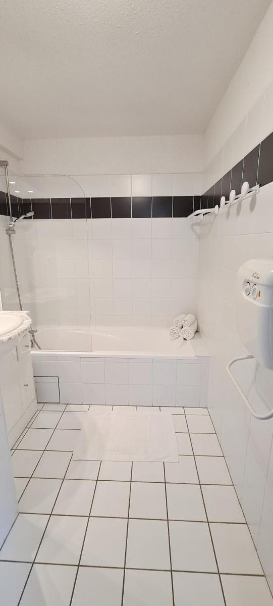 une salle de bain blanche avec une baignoire et un lavabo dans l'établissement Résidence Goélia Les Gorges de la Truyère, à Entraygues-sur-Truyère