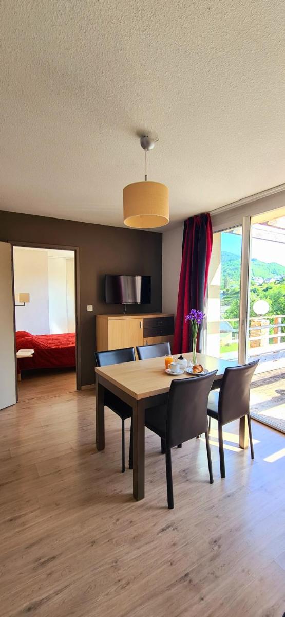 un salon avec une table et des chaises et une chambre dans l'établissement Résidence Goélia Les Gorges de la Truyère, à Entraygues-sur-Truyère