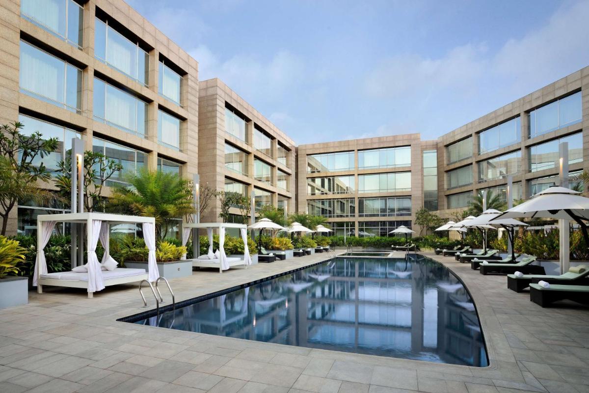 a large building with a swimming pool in front of a building at Hilton Bangalore Embassy GolfLinks in Bengaluru