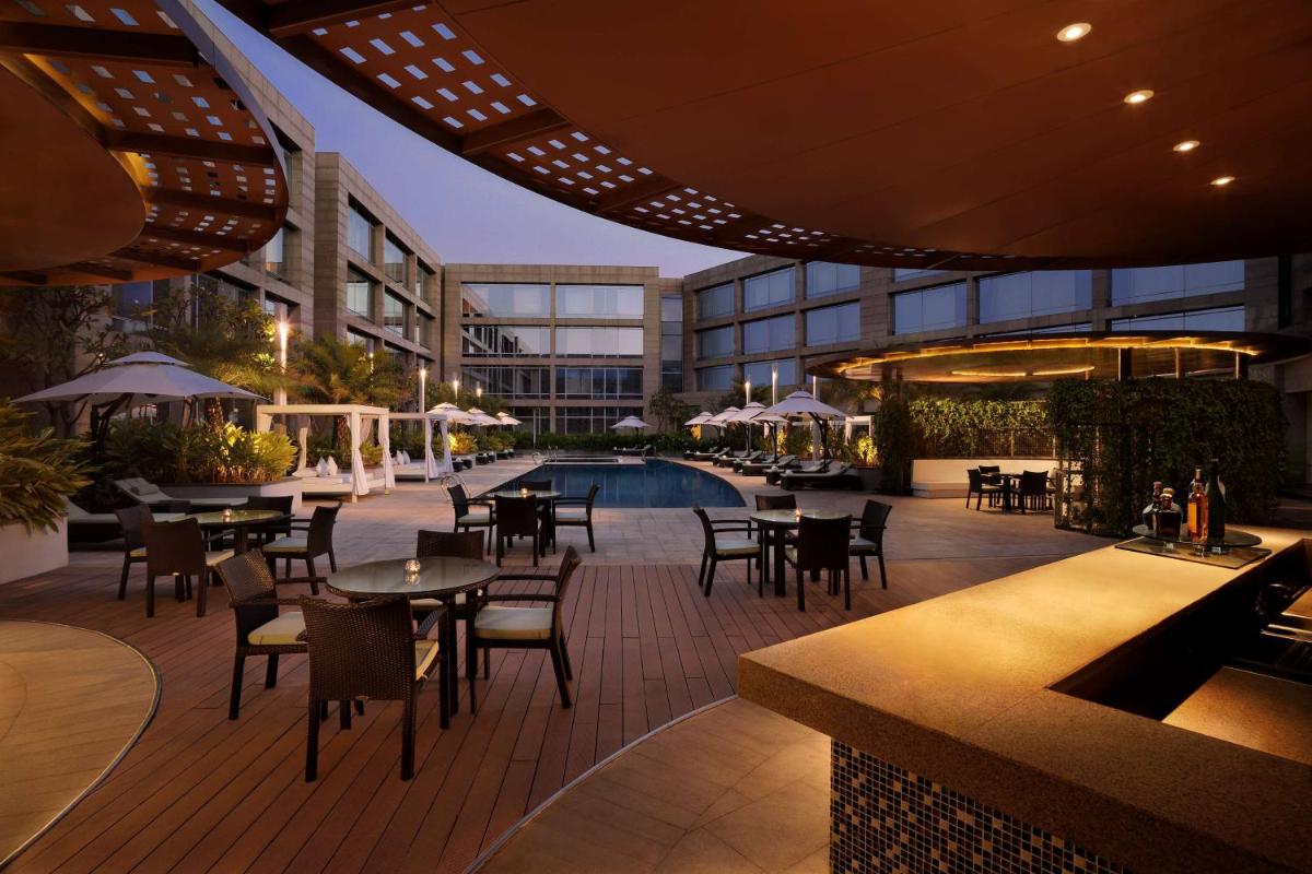 an outdoor patio with tables and chairs and a pool at Hilton Bangalore Embassy GolfLinks in Bengaluru