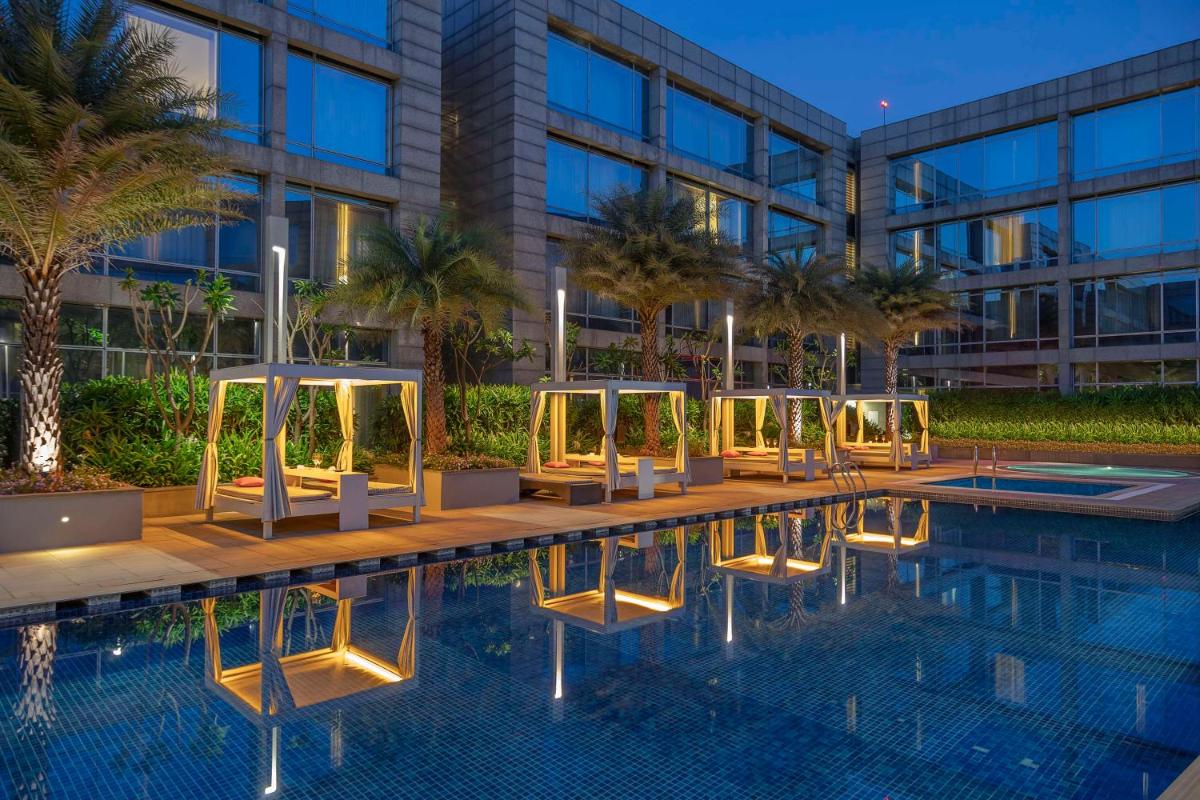 a swimming pool in front of a building at Hilton Bangalore Embassy GolfLinks in Bengaluru a swimming pool in front of a building at Hilton Bangalore Embassy GolfLinks in Bengaluru