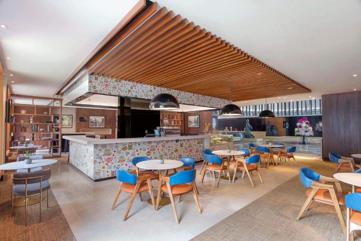 a restaurant with tables and chairs and a bar at Hilton Bangalore Embassy GolfLinks in Bengaluru a restaurant with tables and chairs and a bar at Hilton Bangalore Embassy GolfLinks in Bengaluru