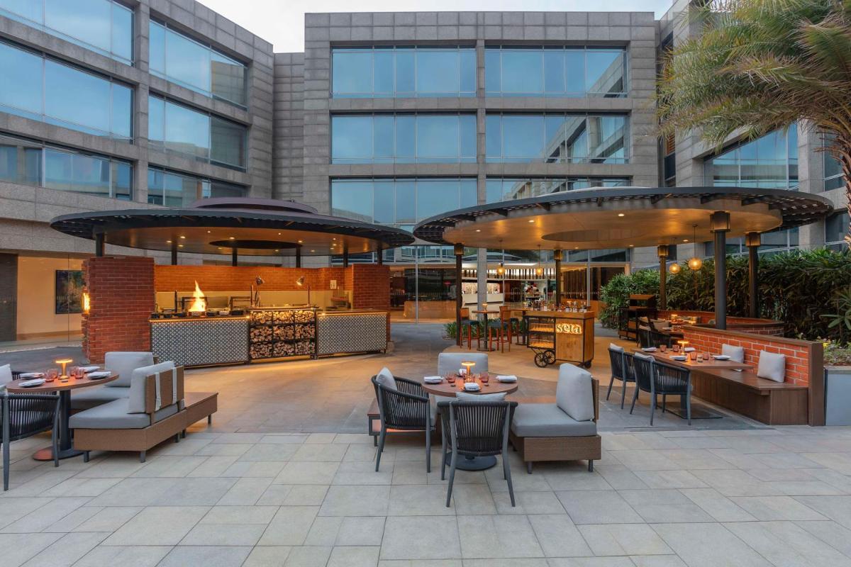 a patio with tables and chairs in a building at Hilton Bangalore Embassy GolfLinks in Bengaluru