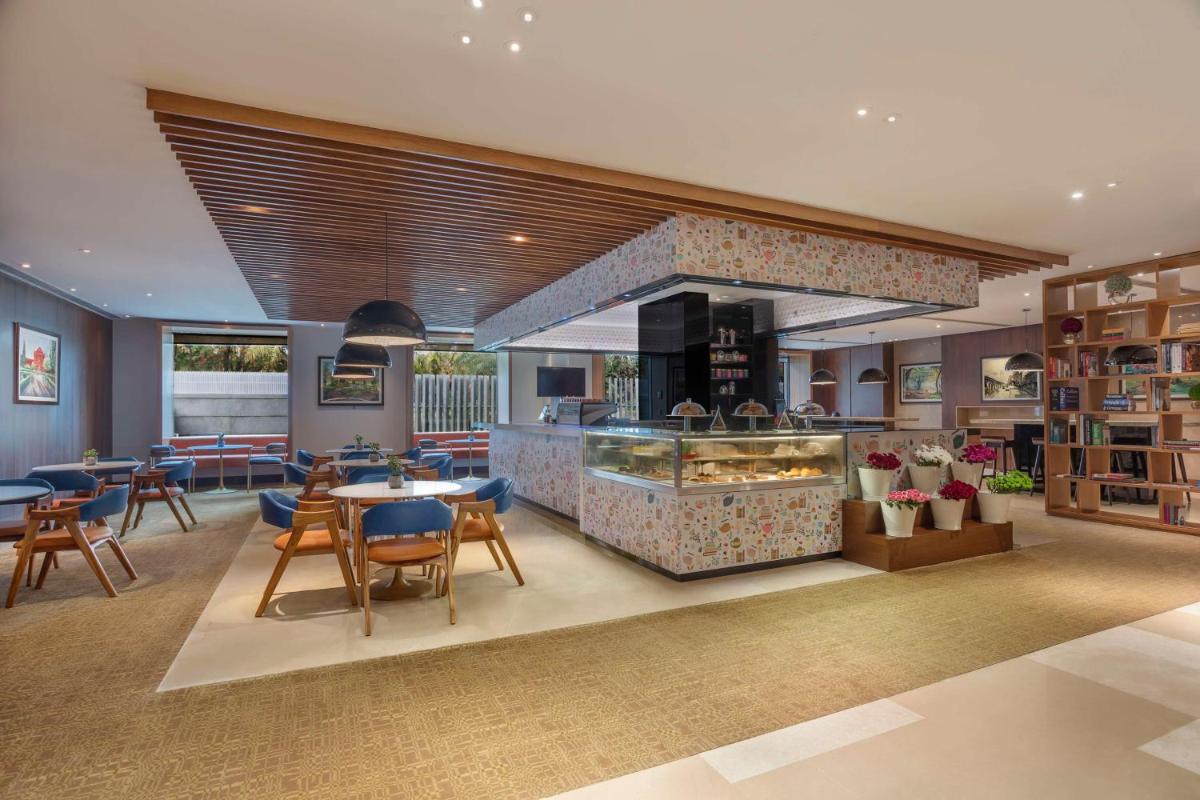 a restaurant with a counter and tables and chairs at Hilton Bangalore Embassy GolfLinks in Bengaluru
