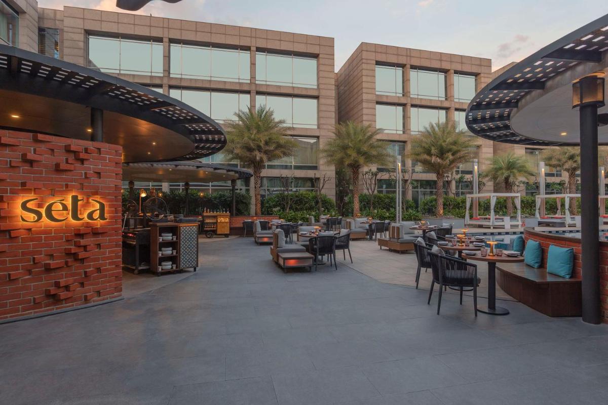 a patio with tables and chairs in front of a building at Hilton Bangalore Embassy GolfLinks in Bengaluru