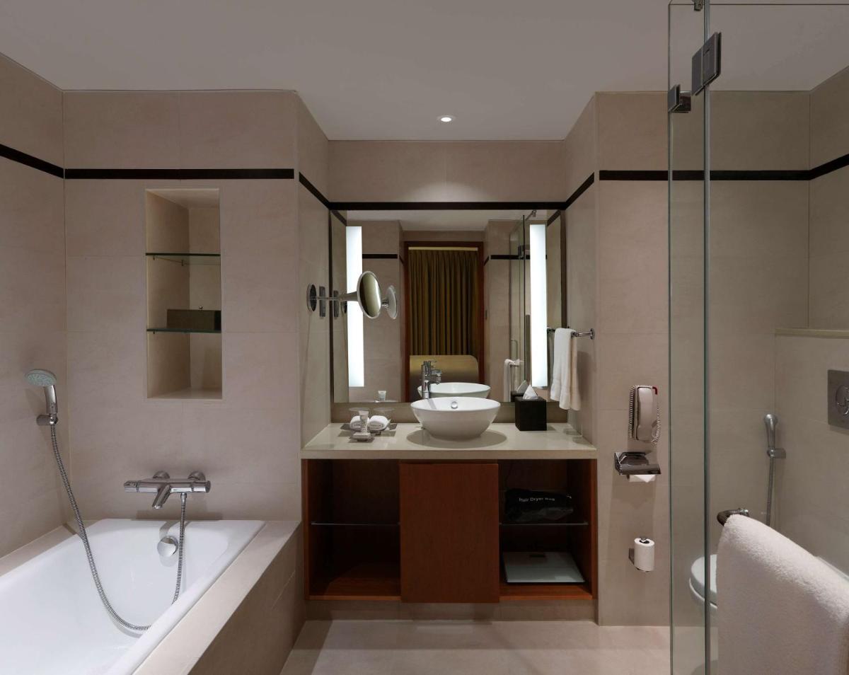 a bathroom with a tub and a sink and a shower at Hilton Bangalore Embassy GolfLinks in Bengaluru