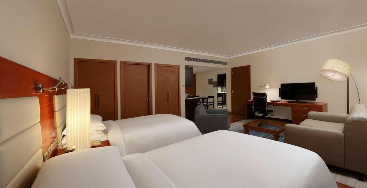 a hotel room with a bed and a living room at Hilton Bangalore Embassy GolfLinks in Bengaluru