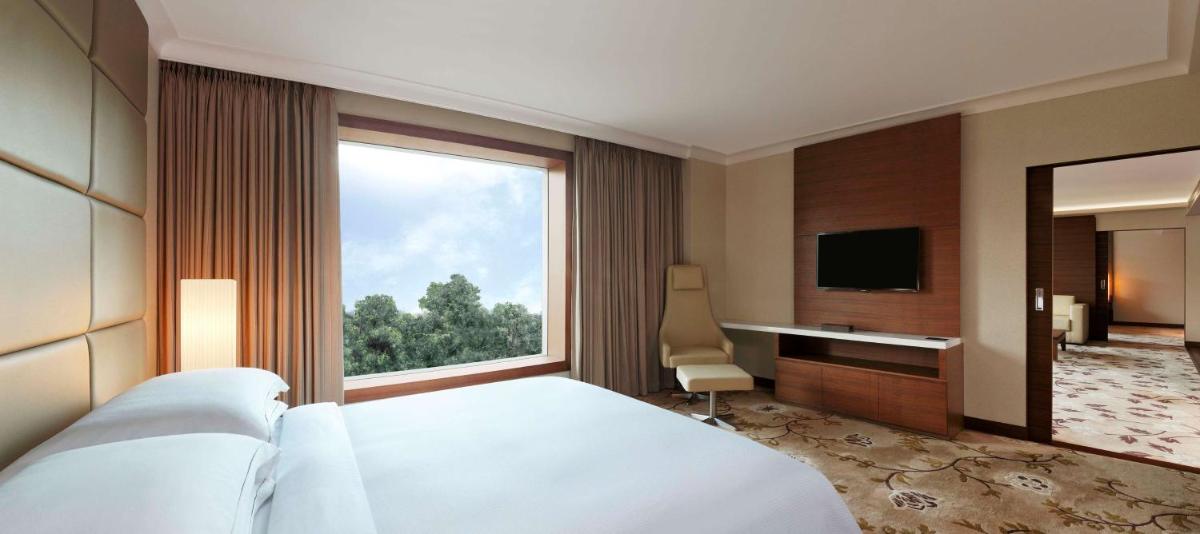 a hotel room with a bed and a large window at Hilton Bangalore Embassy GolfLinks in Bengaluru