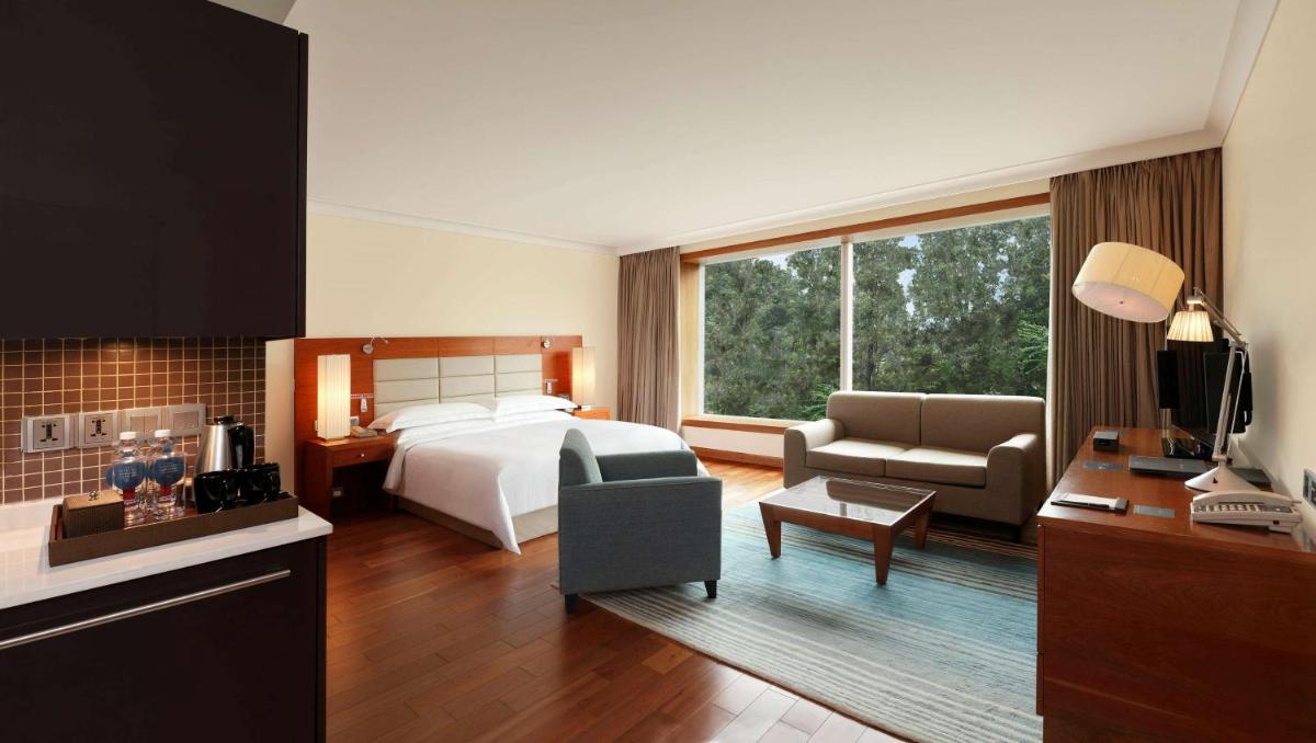 a hotel room with a bed and a living room at Hilton Bangalore Embassy GolfLinks in Bengaluru a hotel room with a bed and a living room at Hilton Bangalore Embassy GolfLinks in Bengaluru