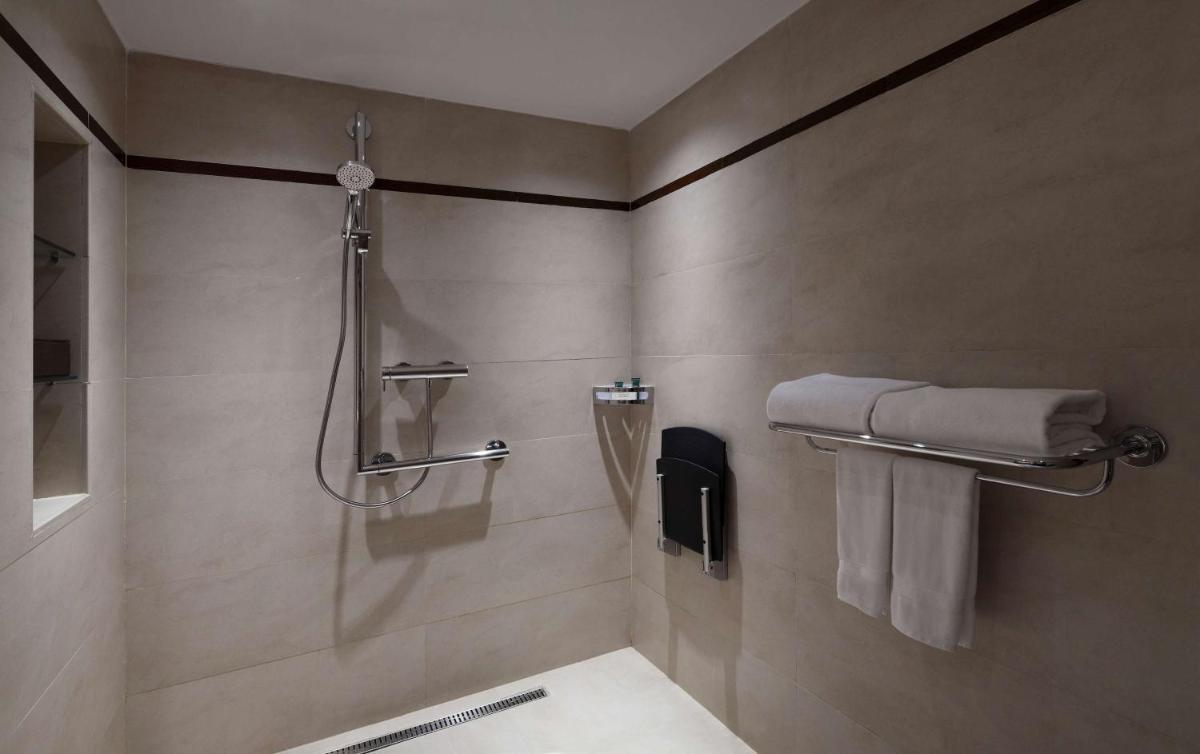 a bathroom with a shower with a sink and towels at Hilton Bangalore Embassy GolfLinks in Bengaluru
