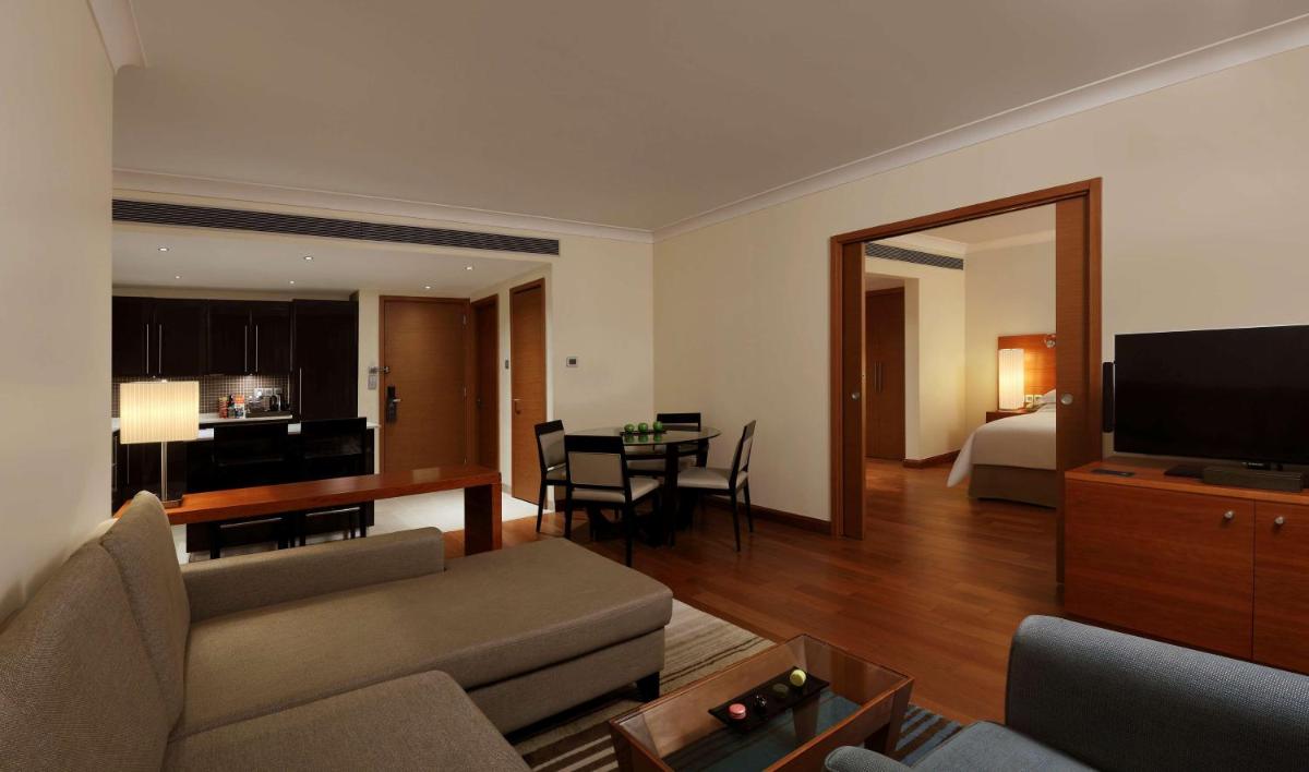 a living room with a couch and a room with a bed at Hilton Bangalore Embassy GolfLinks in Bengaluru