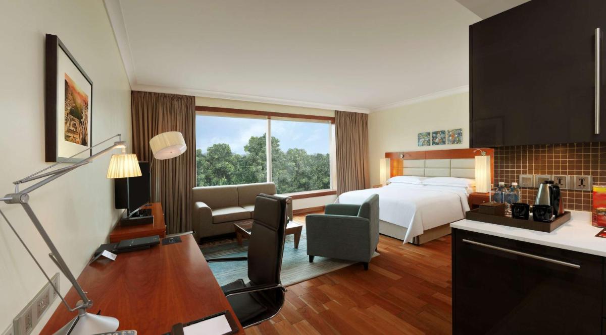 a hotel room with a bed and a kitchen at Hilton Bangalore Embassy GolfLinks in Bengaluru