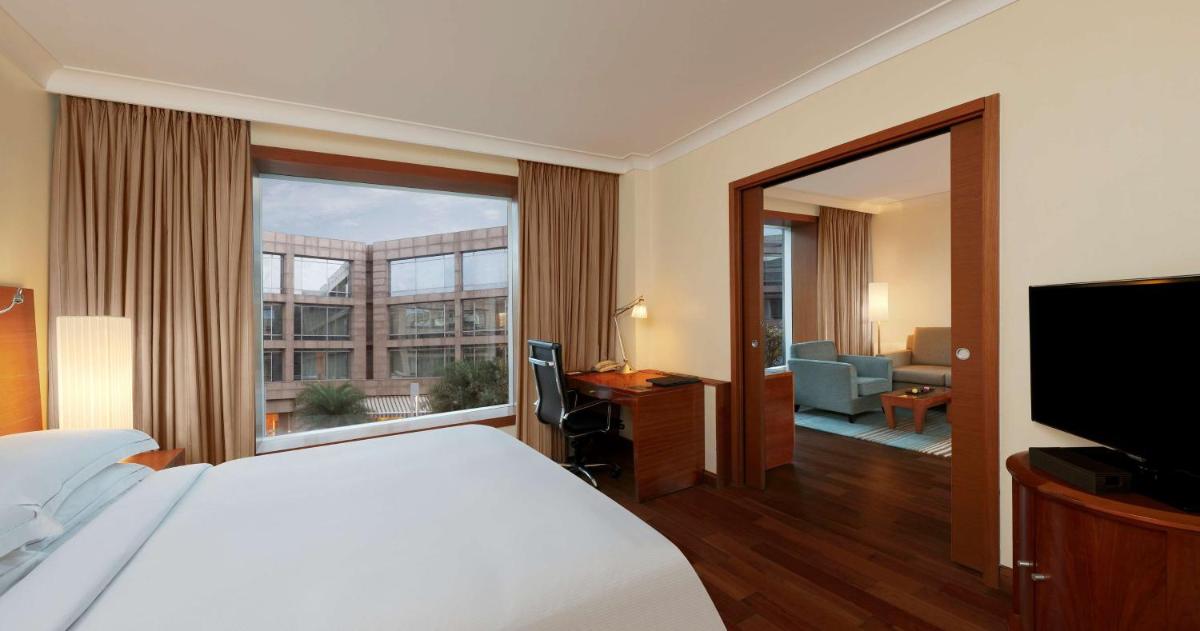 a hotel room with a bed and a large window at Hilton Bangalore Embassy GolfLinks in Bengaluru