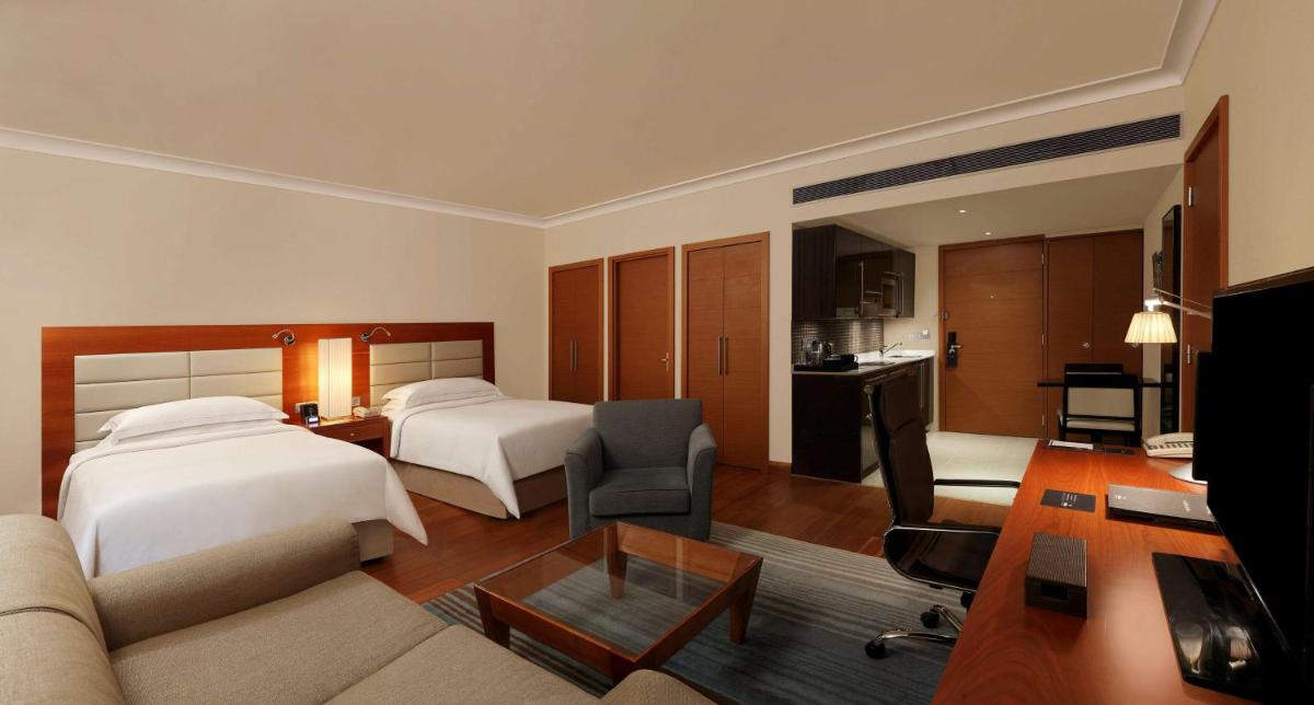 a hotel room with two beds and a living room at Hilton Bangalore Embassy GolfLinks in Bengaluru