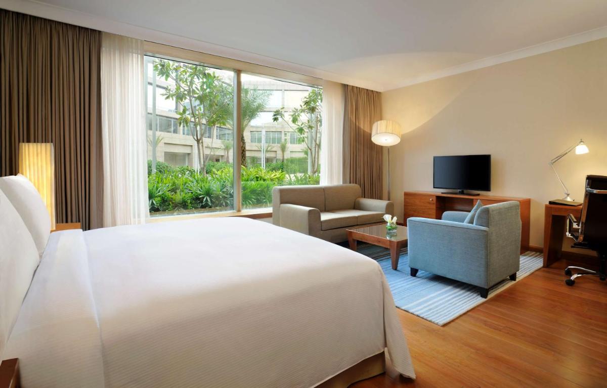 a hotel room with a bed and a large window at Hilton Bangalore Embassy GolfLinks in Bengaluru