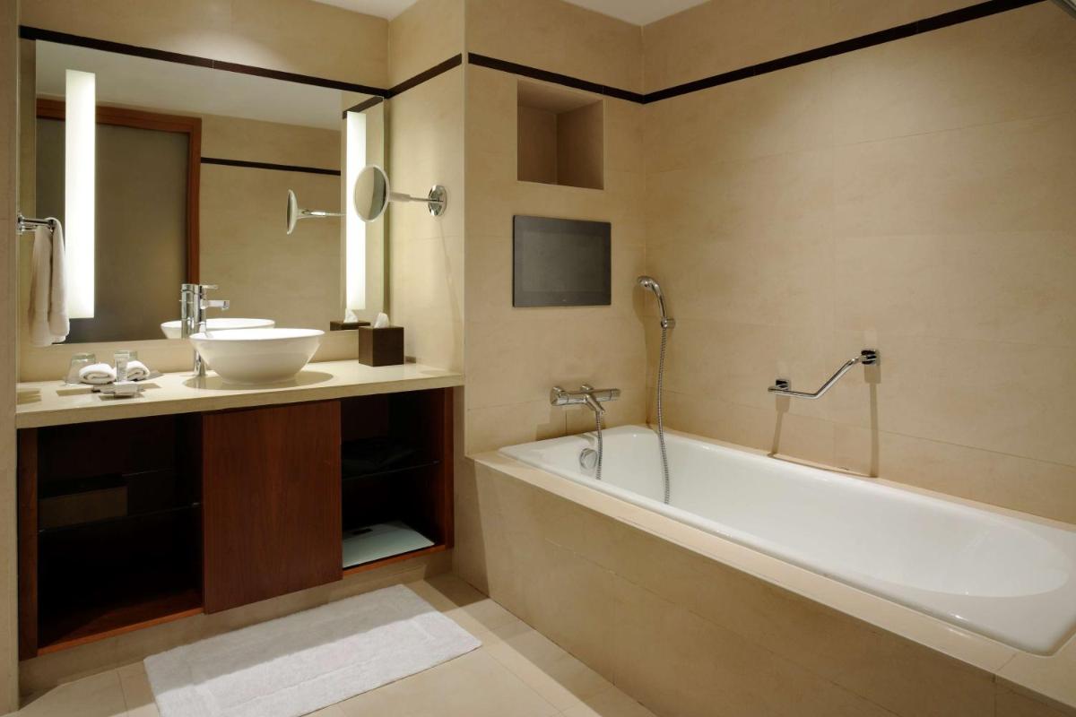 a bathroom with a bath tub and a sink at Hilton Bangalore Embassy GolfLinks in Bengaluru