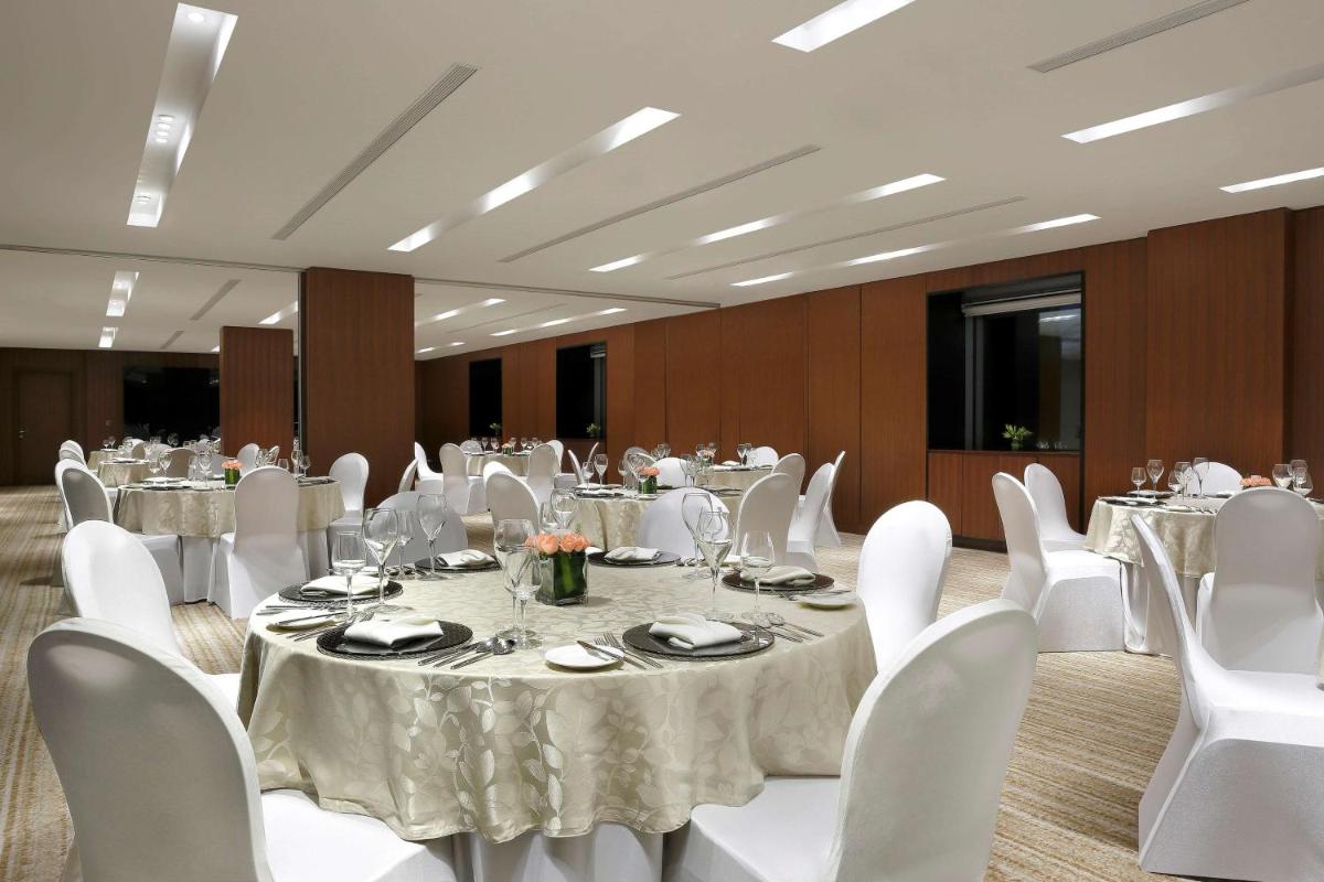 a banquet hall with white tables and white chairs at Hilton Bangalore Embassy GolfLinks in Bengaluru