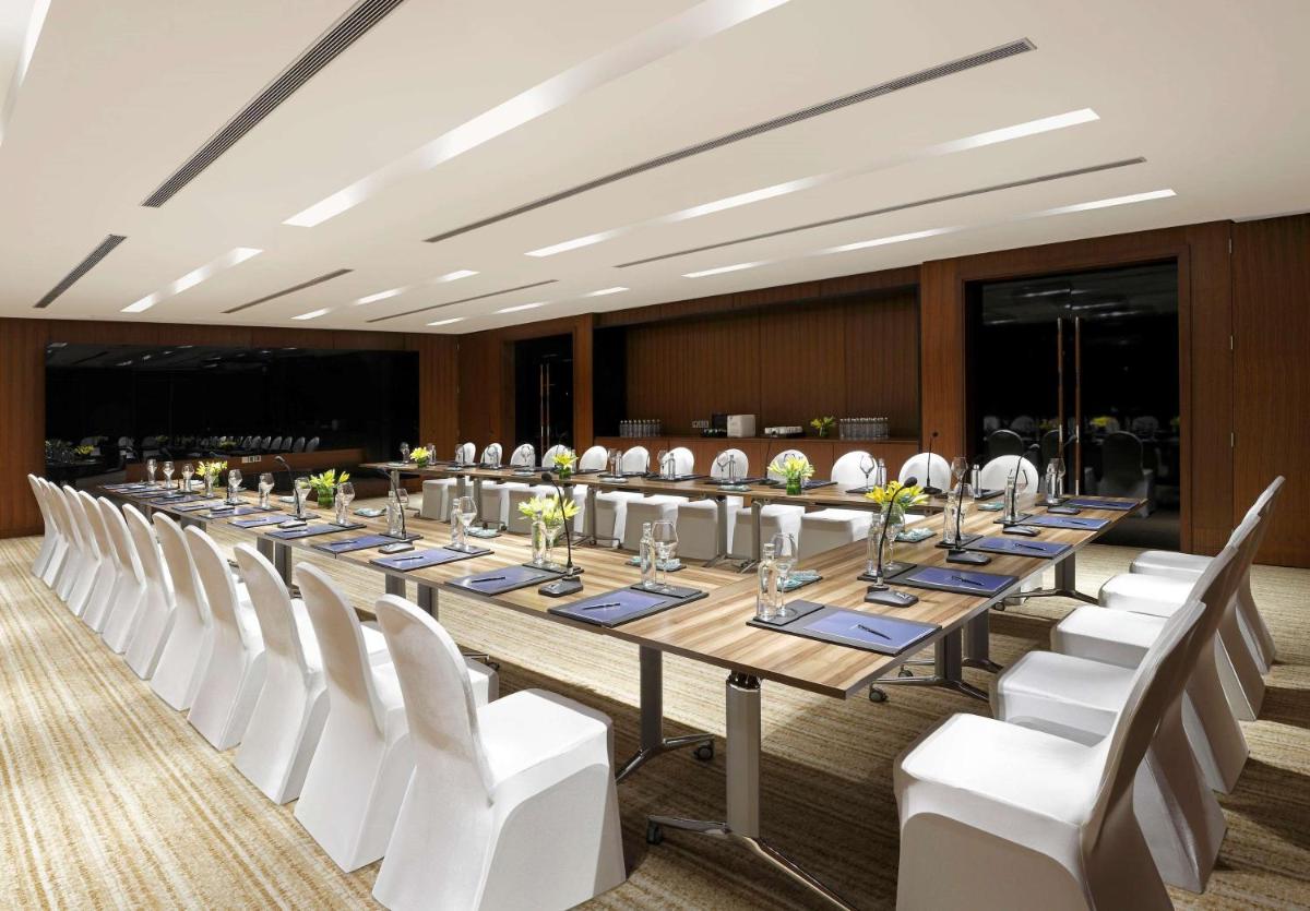 a large conference room with a long table and white chairs at Hilton Bangalore Embassy GolfLinks in Bengaluru