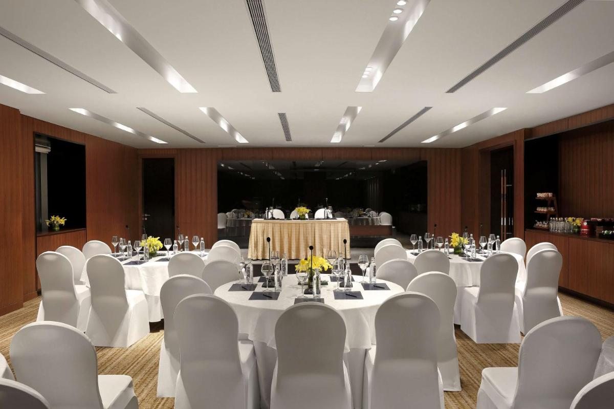 a banquet hall with white tables and white chairs at Hilton Bangalore Embassy GolfLinks in Bengaluru