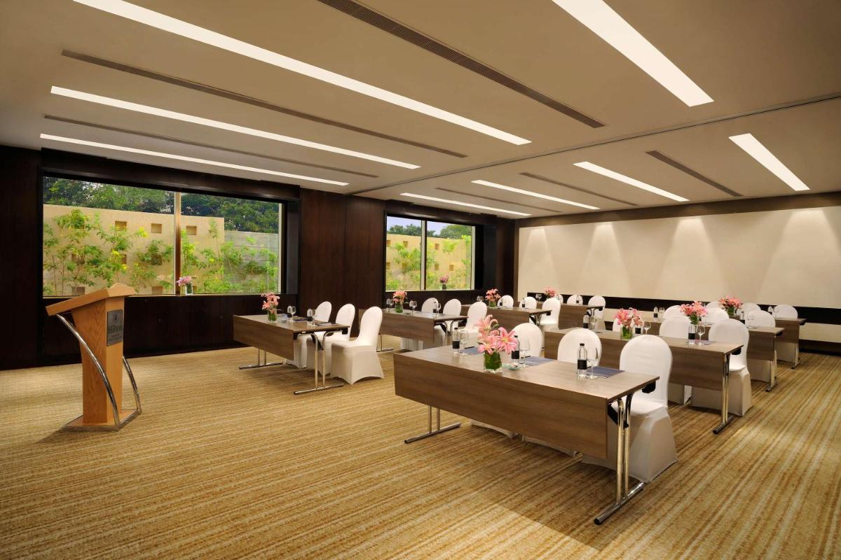 a conference room with tables and chairs and a podium at Hilton Bangalore Embassy GolfLinks in Bengaluru
