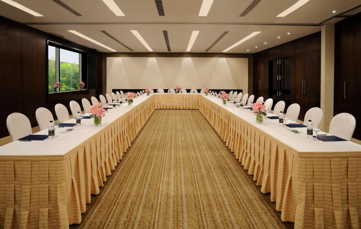 a large conference room with long tables and chairs at Hilton Bangalore Embassy GolfLinks in Bengaluru