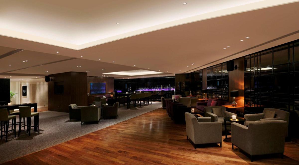 a hotel lobby with chairs and tables and a bar at Hilton Bangalore Embassy GolfLinks in Bengaluru