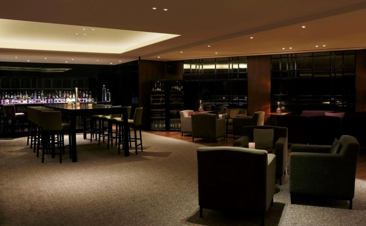 a restaurant with a bar with tables and chairs at Hilton Bangalore Embassy GolfLinks in Bengaluru