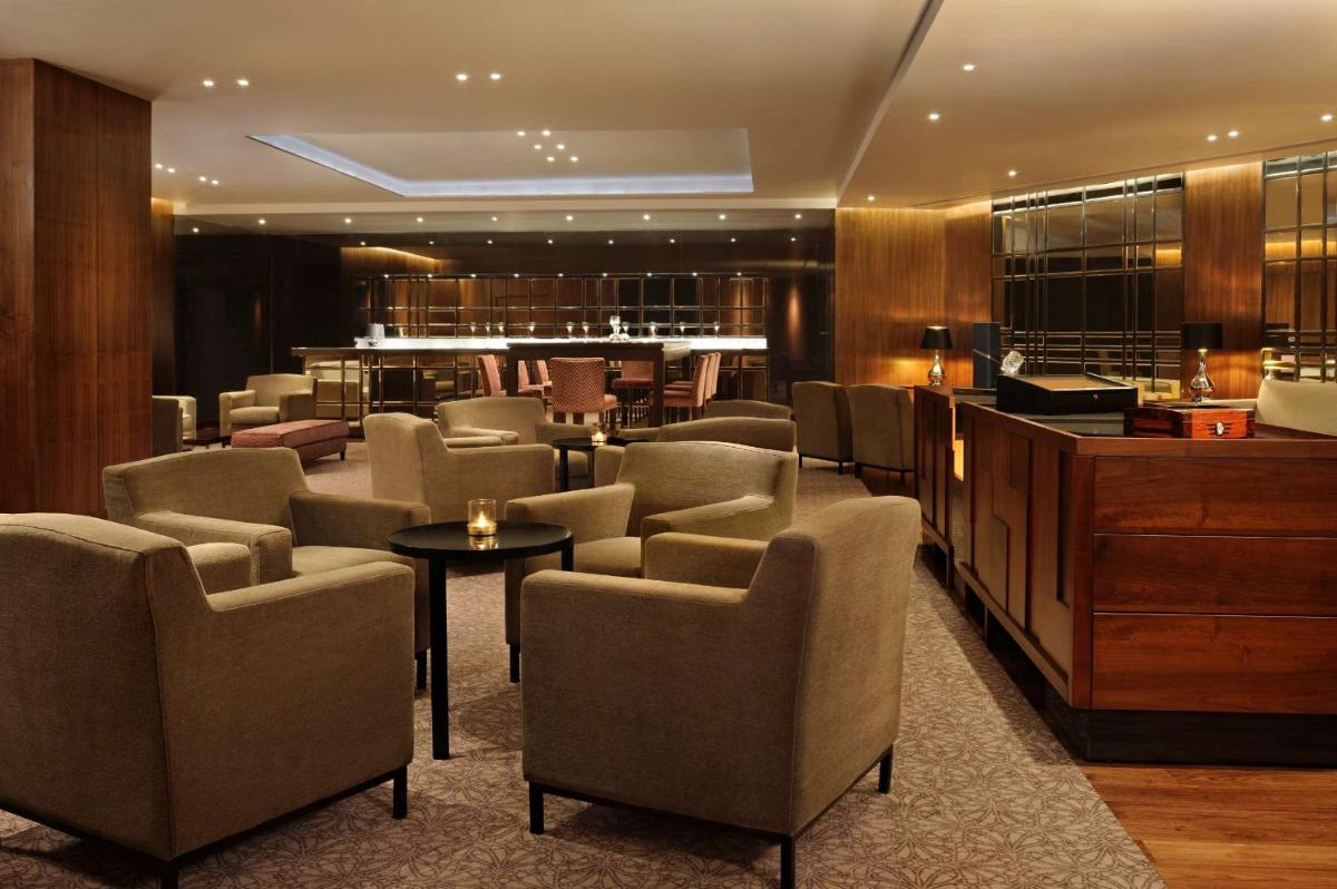 a waiting room with chairs and a bar in a hotel at Hilton Bangalore Embassy GolfLinks in Bengaluru