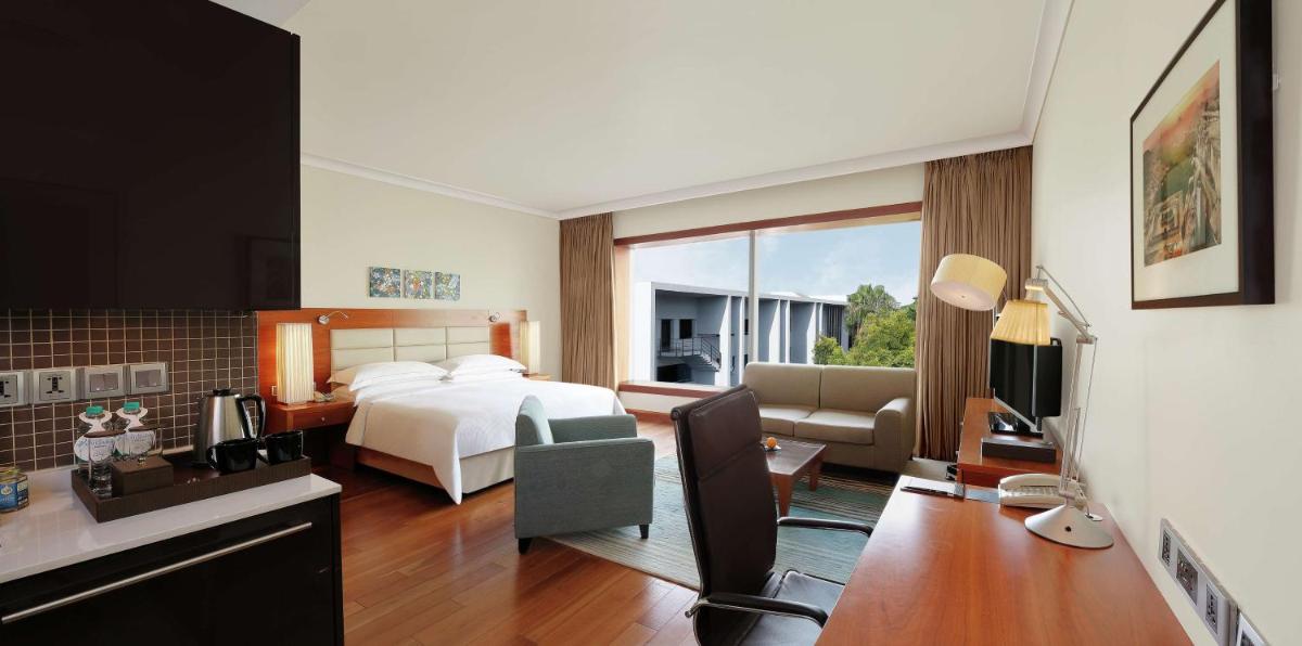a hotel room with a bed and a living room at Hilton Bangalore Embassy GolfLinks in Bengaluru