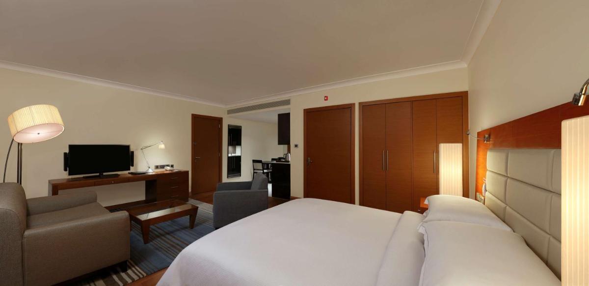 a hotel room with a bed and a couch and a television at Hilton Bangalore Embassy GolfLinks in Bengaluru