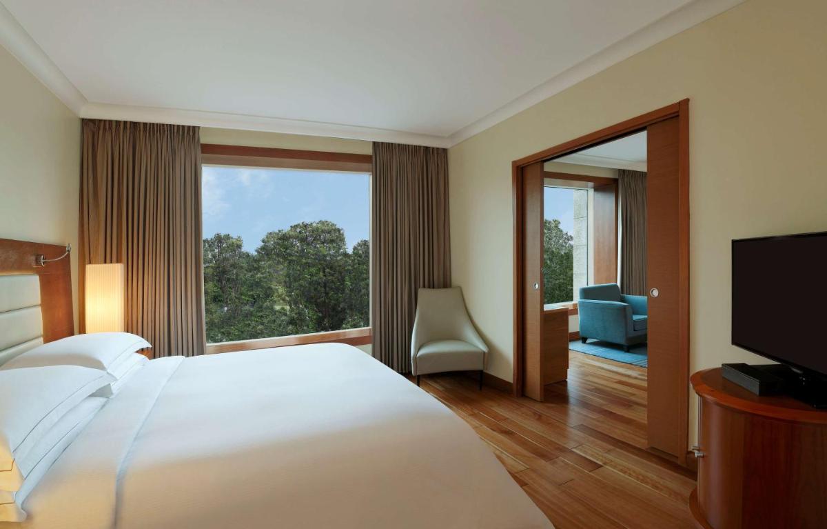 a hotel room with a large bed and a large window at Hilton Bangalore Embassy GolfLinks in Bengaluru