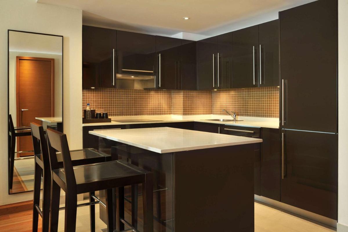 a kitchen with black cabinets and a island with chairs at Hilton Bangalore Embassy GolfLinks in Bengaluru