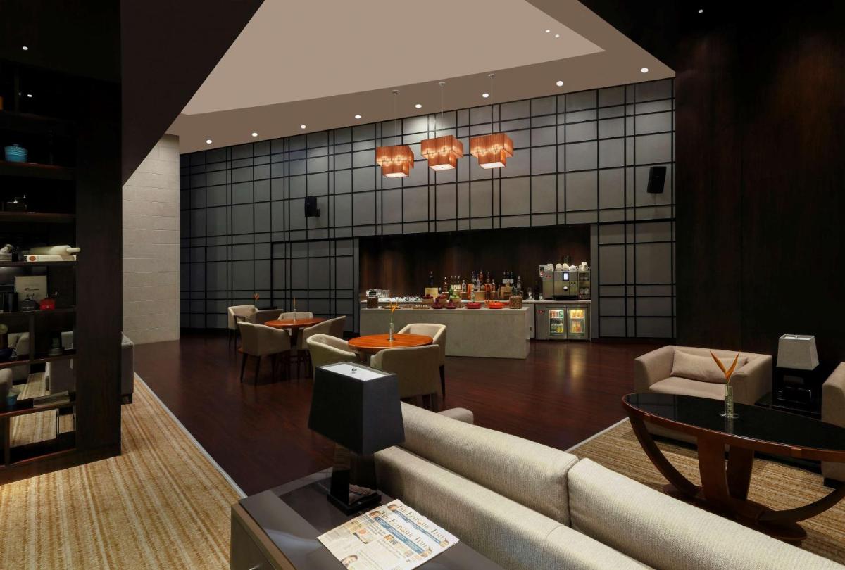 a lobby with a couch and tables and a bar at Hilton Bangalore Embassy GolfLinks in Bengaluru
