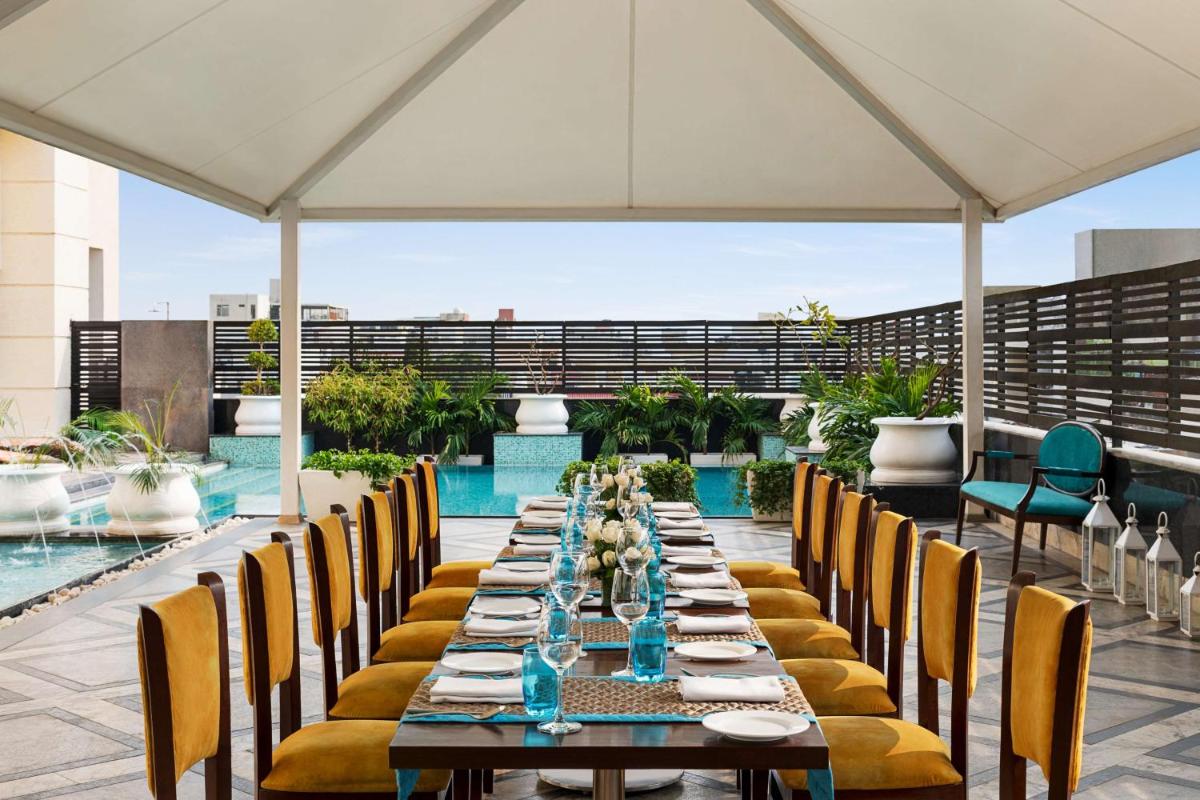 a long dining table with chairs and a pool at Hilton Jaipur in Jaipur a long dining table with chairs and a pool at Hilton Jaipur in Jaipur