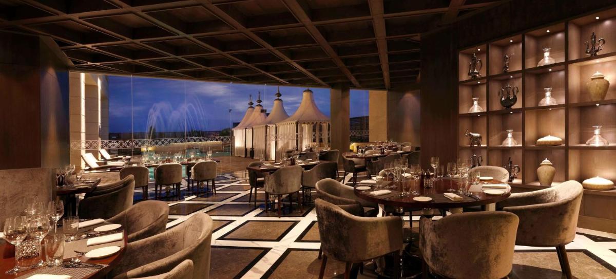 a restaurant with tables and chairs in a room at Hilton Jaipur in Jaipur a restaurant with tables and chairs in a room at Hilton Jaipur in Jaipur