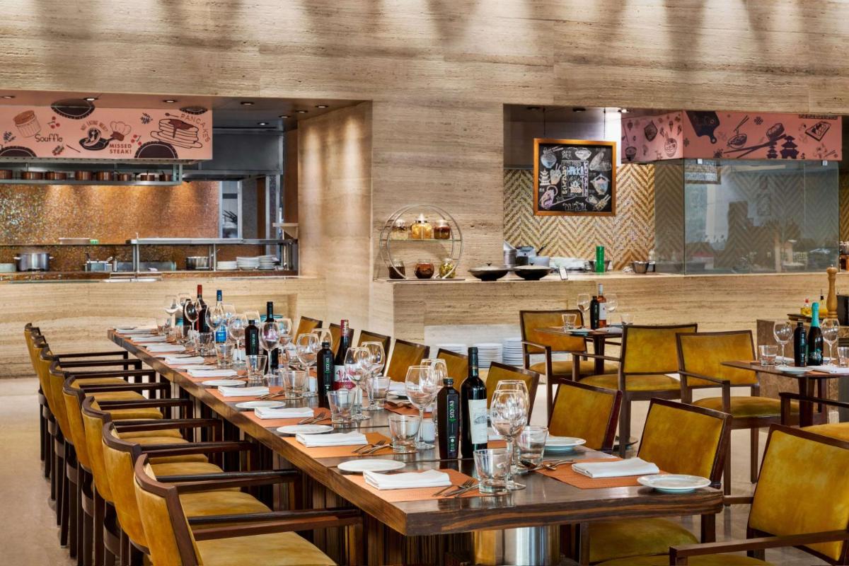 a restaurant with a long table with wine bottles at Hilton Jaipur in Jaipur a restaurant with a long table with wine bottles at Hilton Jaipur in Jaipur