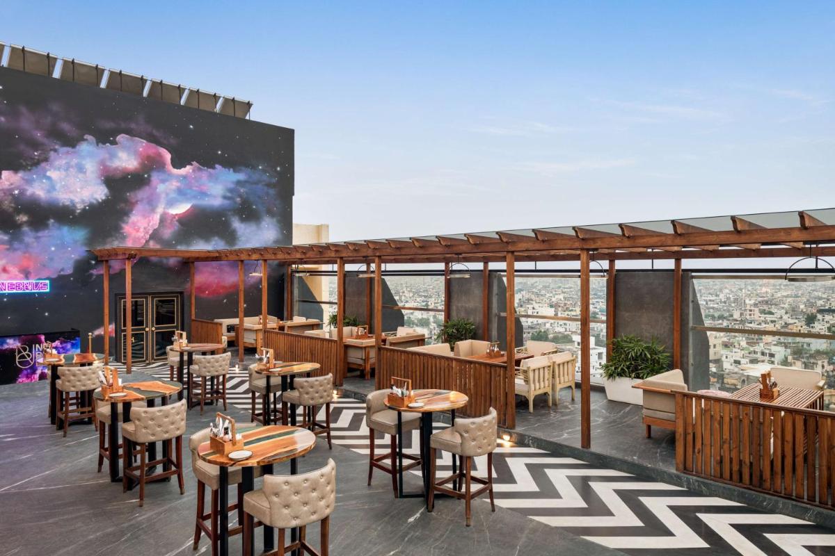 a rendering of a restaurant with tables and chairs at Hilton Jaipur in Jaipur a rendering of a restaurant with tables and chairs at Hilton Jaipur in Jaipur