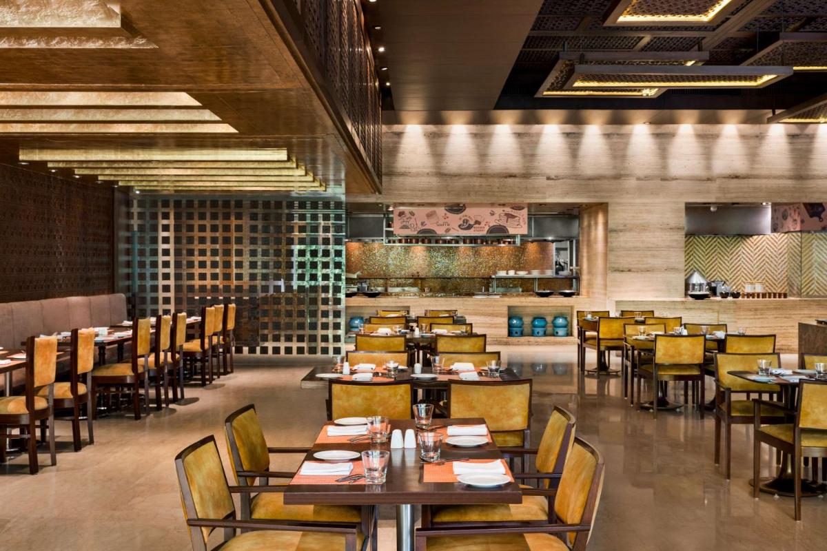 a dining room with tables and chairs and a restaurant at Hilton Jaipur in Jaipur a dining room with tables and chairs and a restaurant at Hilton Jaipur in Jaipur