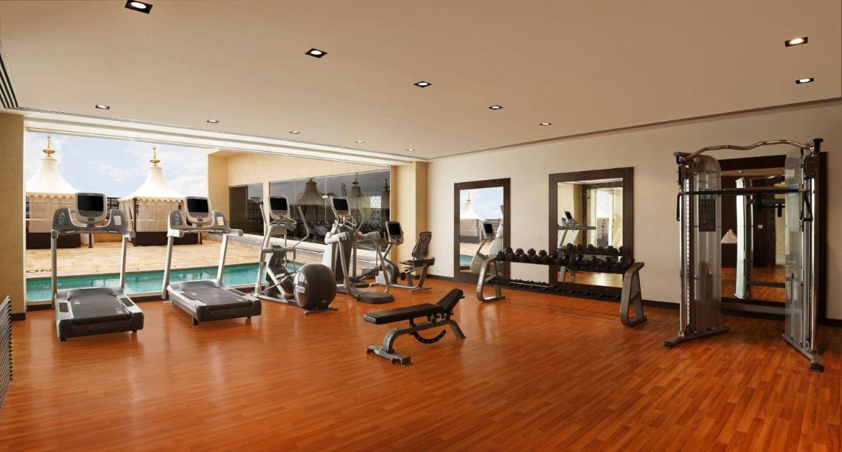 a gym with exercise equipment and a swimming pool at Hilton Jaipur in Jaipur a gym with exercise equipment and a swimming pool at Hilton Jaipur in Jaipur