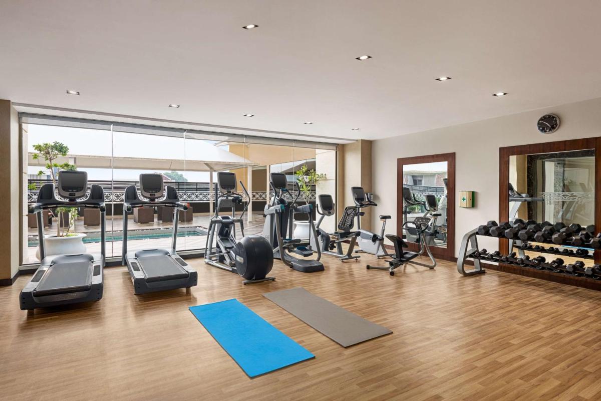 a gym with several treadmills and exercise bikes at Hilton Jaipur in Jaipur a gym with several treadmills and exercise bikes at Hilton Jaipur in Jaipur