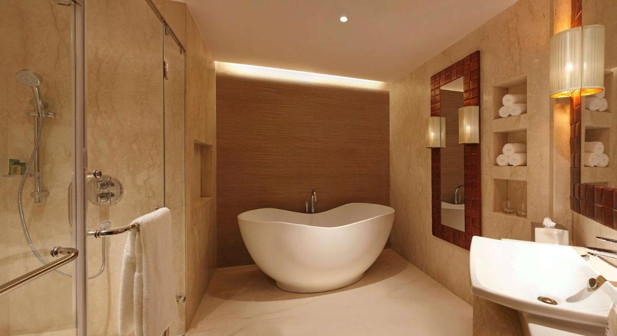 a bathroom with a bath tub and a sink at Hilton Jaipur in Jaipur a bathroom with a bath tub and a sink at Hilton Jaipur in Jaipur