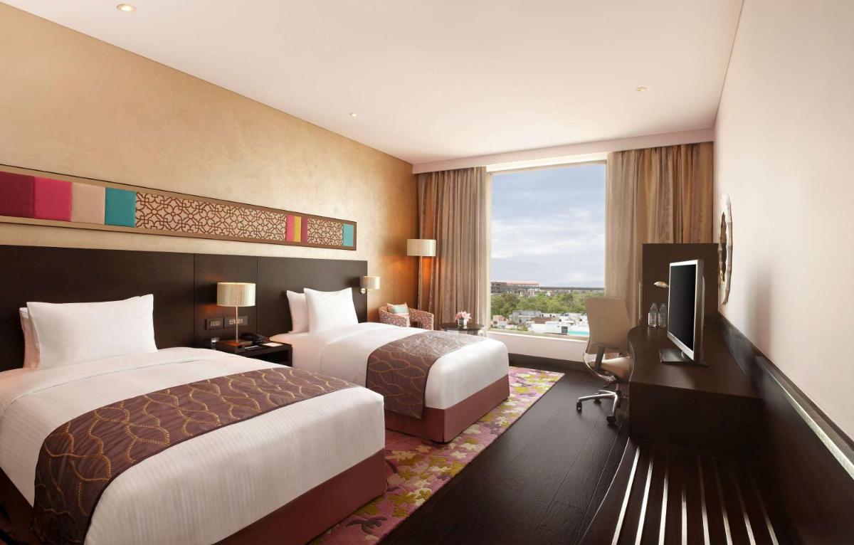 a hotel room with two beds and a television at Hilton Jaipur in Jaipur a hotel room with two beds and a television at Hilton Jaipur in Jaipur